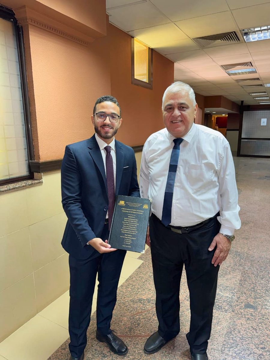 Hosam Dyab with his graduation project supervisor, holding the ClassTrack thesis book